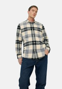 Flanellen overhemd met een grijs, zwart en crème ruitpatroon, voorzien van een knoopsluiting aan de voorkant, een kraag en twee borstzakken. Draag het met blauwe jeans.