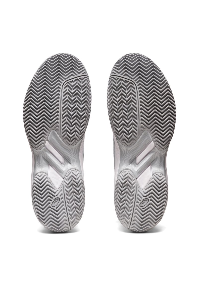 Zapatillas deportivas blancas con una suela de goma texturizada en gris que presenta un patrón de espiga y un logo de la marca para una mejor tracción y soporte.
