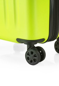 Maleta rígida de color verde brillante, con superficie texturizada, acentos negros y ruedas de rodaje suave que presentan un diseño de flores.