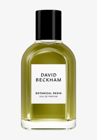 Klare Glasflasche mit runder Form, gefüllt mit grünem Flüssigkeit. Schwarzer Deckel, weißes Etikett mit schwarzem Text: "DAVID BECKHAM BOTANICAL RESIN."