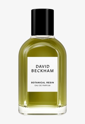 Bouteille en verre transparent de forme arrondie, remplie d'un liquide vert. Capuchon noir, étiquette blanche avec texte noir : "DAVID BECKHAM BOTANICAL RESIN."