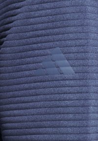 Dunkelblaues Sportshirt mit gerippter Struktur, versehen mit einem erhabenen Drei-Streifen-Logo auf der linken Seite. Weiches, leichtes Material.