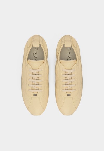 Ζευγάρι μπεζ δερμάτινα casual παπούτσια με κορδόνια, στρογγυλεμένες μύτες, μαλακά επενδυμένα περιλαίμια και διακριτικό λογότυπο της μάρκας στην κορυφή.