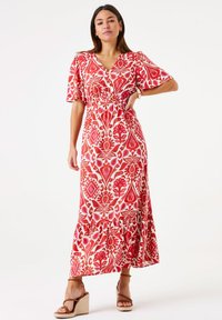 Maxi-jurk in een levendig rood en wit bloemmotief met korte mouwen, een diepe V-halslijn en een elastische taille, voorzien van een volantszoom.