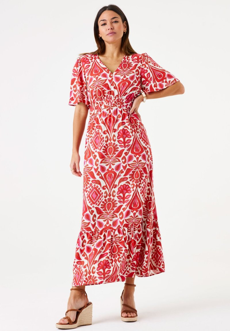 Maxi-jurk in een levendig rood en wit bloemmotief met korte mouwen, een diepe V-halslijn en een elastische taille, voorzien van een volantszoom.