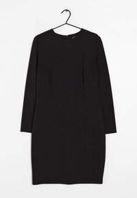 Vestido negro de mangas largas con cuello redondo, forma ajustada, tejido texturizado y costuras laterales. Se cierra con una cremallera en la parte posterior.