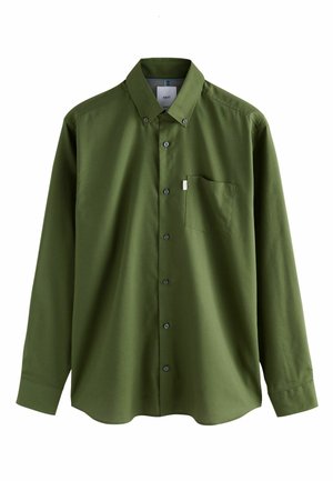 Dlhá olivovo zelená košeľa na gombíky s gombíkovým golierom a náprsní vreckom, zobrazená na jednoduchom bielom pozadí.