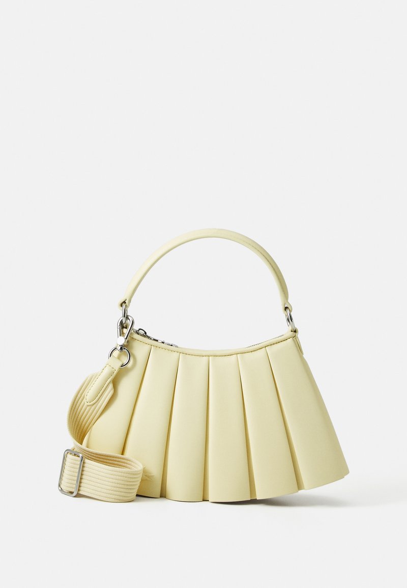 Pleated handbag in soft yellow material with a curved handle. Features a removable adjustable strap and smooth texture with minimal hardware.