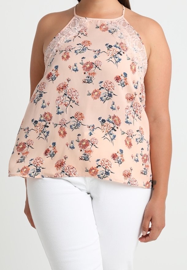 Haut sans manches pêche à col licou avec bordure en dentelle et imprimé floral, porté avec un pantalon blanc, présenté sur une personne de la nuque aux hanches.