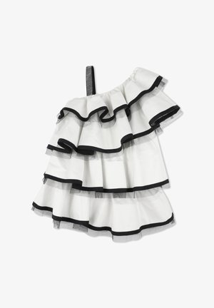 Robe asymétrique avec volants superposés en blanc et noir. Bordure noire sur chaque couche et une sangle scintillante. Texture de tissu lisse.