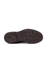Zool van een donkerbruine schoen met ronde rubberen noppen voor grip, inclusief een logo dat is ingebed nabij het booggebied.