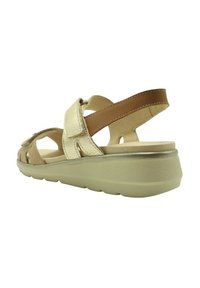 Sandalia dorada y marrón con un upper metálico texturizado, diseño abierto y suela acolchada. Presenta correas ajustables y detalles recortados.