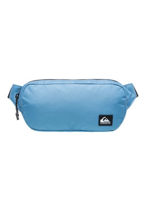 Blue fabric fanny pack with a smooth texture, rounded shape, and a black logo patch. Features a zipper and adjustable straps on the sides.
