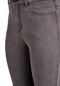 Jeans en denim gris foncé avec une coupe slim, design classique à cinq poches, avec des coutures visibles et une texture lisse.