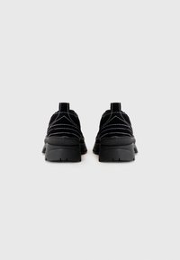 Mustad nubukist sneakerid tekstuurset viimistlust, kontrastset valget õmblust ja volüümikat musta tallat, seljal tõmbetabaga.