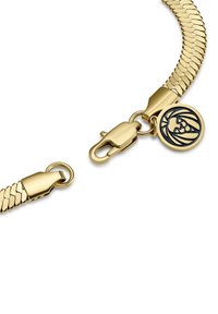 Gullfarget armbånd med et fleksibelt, kjede-lignende design. Har en hummerlås og en rund charm med et løvemotiv. Glatt tekstur.
