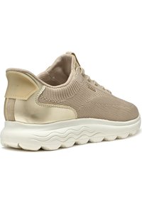 Sneaker beige con tomaia in tessuto knit, accenti metallici dorati e suola bianca imbottita con motivi a onda. Branding Geox sul tallone.
