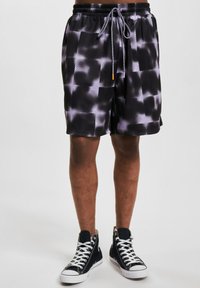 Svarte og grå mønstrete treningsshorts med mesh-textur, elastisk midje og snor. Sammen med svarte høyhælte joggesko.