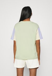 Tričko s krátkým rukávem v zelené, pastelově fialové a béžové barvě. Měkký bavlněný materiál s volným střihem a minimalistickým designem.