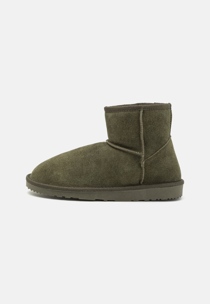 Bottines en daim vert olive avec un bout arrondi, des détails cousus et une semelle en caoutchouc texturée basse.
