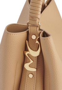 Borsa a mano in pelle beige con una superficie liscia, dotata di una maniglia intrecciata e accessori in oro, inclusi un logo decorativo e un dettaglio con bottone a pressione.