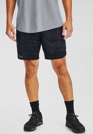 Czarne sportowe spodenki z fakturowanym wzorem, panelami z siateczki i wygodnym krojem, zestawione z czarnymi butami treningowymi i skarpetami za kostkę.