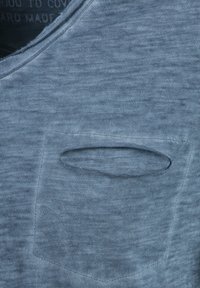 Camiseta de algodón azul de manga corta con un escote redondo y un bolsillo frontal con una abertura en forma de hendidura, tela texturizada.