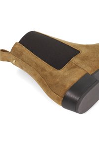 Brown suede ankle boot with a black elastic side panel, rounded toe, and a low, chunky heel. Gold logo detail on the side.