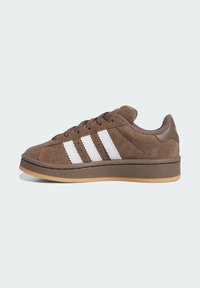 Brown suede sneakers featuring three white stripes, rubber sole, and contrasting darker accents on the heel and laces.