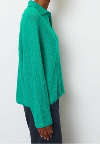 Cabled knit sweater in bright green, featuring a collared neckline and long sleeves, with a relaxed, cropped fit and soft texture.