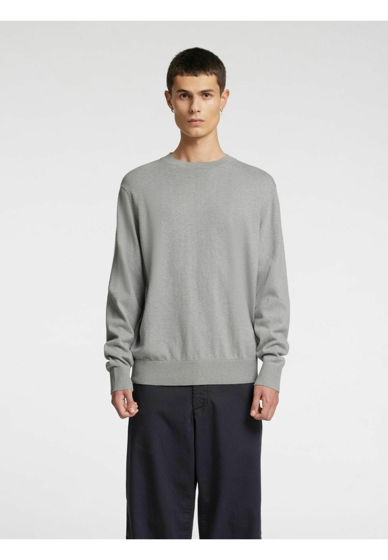 Grå langermet genser laget av mykt stoff, med rund hals og ribbestrikkede mansjetter og nederkant, kombinert med mørke bukser.