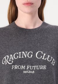 Grau gestrickter Pullover aus Wolle mit einem gerippten Halsausschnitt und einem Textdesign in Off-White: "RACING CLUB FROM FUTURE EST.2018." Weiche Textur.