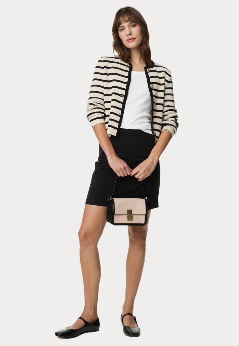 Randig, krämfärgad och svart cardigan med guldfärgad knappar, parat med en vit linne, svart kjol och en liten beige och svart handväska. Svarta lägenheter.
