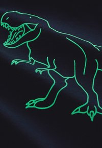 Musta kangas esittelee hohtavaa vihreää viivaa dinosauruksesta, jossa on tarkat kynnet, hampaat ja dynaaminen asento.