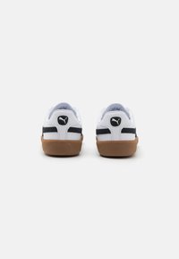 Zapatillas blancas con rayas azul marino, cuello acolchado y suela de goma. Presenta un logo en la parte trasera y parte superior de cuero suave.