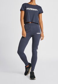 Námořnický sportovní krájený tričko a legíny set s velkým bílým logem "HUMMEL" a kontrastními akcenty. Měkká, pružná látka.