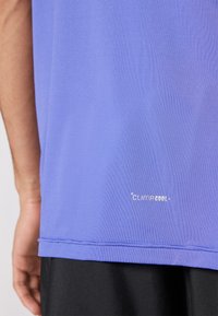 Purple athletic shirt made from lightweight fabric, featuring a CLIMACOOL logo near the hem and a smooth texture.