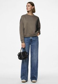 Felpa grigia scura con scollatura tonda, abbinata a jeans a vita alta larghi blu. Borsa nera con texture arricciata.