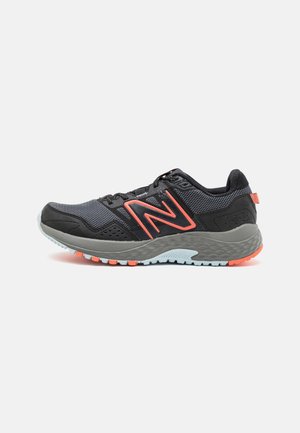 Chaussure de course noire et grise avec des touches orange, dessus en tissu mesh, semelle rembourrée et logo de la marque sur le côté.