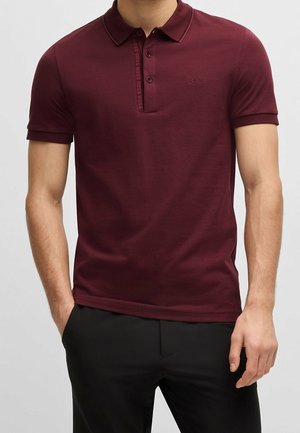 Bordowa koszulka polo z klasycznym kołnierzykiem, krótkimi rękawami, subtelnym haftem logo oraz kontrastowym wykończeniem przy listwie guzików.