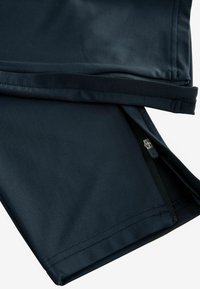 Pantalones deportivos navy fabricados con un tejido suave, que cuentan con un bolsillo con cremallera y detalles de dobladillo cosidos. Corte relajado con piernas ajustadas.