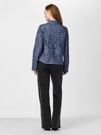 Blue lace jacket featuring intricate floral patterns and a collar, paired with black straight-leg pants. The texture is sheer and layered.