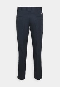 Un pantalon bleu marine en tissu lisse et résistant, avec une coupe droite, des poches arrière et un petit logo sur la ceinture.