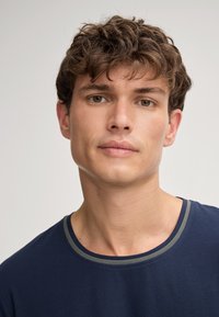 Maglietta di cotone blu navy con scollo rotondo e bordo grigio a contrasto. Tessuto liscio, vestibilità casual e design minimalista.