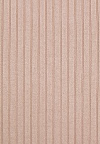 Zbliżenie na beżową dzianinę z pionowym prążkowanym wzorem, z naprzemiennymi szerokimi i wąskimi paskami.