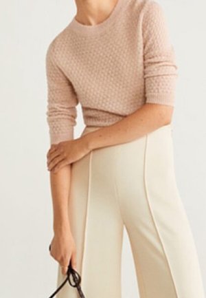 Hellrosa strukturierter Pullover mit Rundhalsausschnitt und 3/4-Ärmeln, kombiniert mit cremefarbenen, weiten Hosen. Schwarze Accessoires.