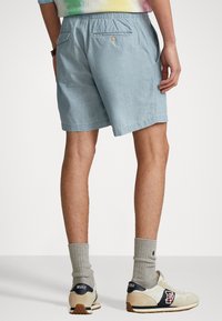 Ljusblå chambray-shorter med resårlinning, sidofickor och en knäppt bakficka. Matchas med grå strumpor och sneakers i retrostil.