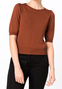 Short-sleeve, rust-colored knit top with ribbed hem and cuffs, featuring a round neckline and a smooth texture.