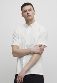 Weißes Kurzarmhemd aus leichtem Stoff mit Button-Down-Kragen, gerader Säume und minimalistischem Design.