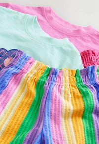 Růžová a mentolově zelená trička s kulatým výstřihem spojená s barevnými proužkovanými kalhotami s elastickým pasem v barvách fialové, modré, růžové, žluté, zelené a oranžové.